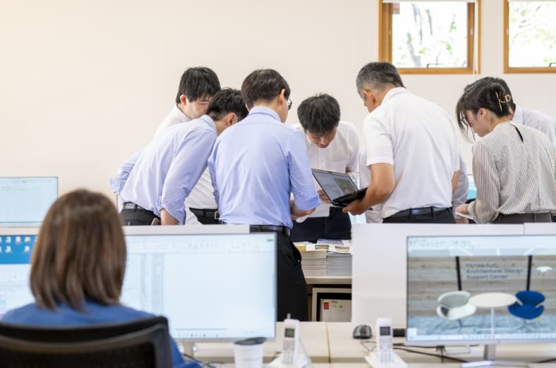 複数人の社員が一箇所に集まって話し合う様子